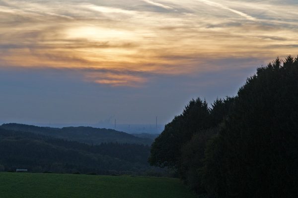 Sunday sun set in the countryside with the distant smoke stacks spewing smoke.